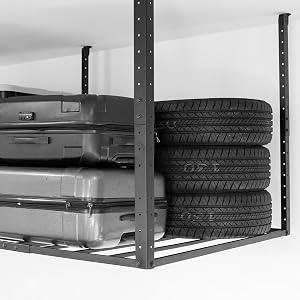 Four tires stacked on a rack beside stored luggage